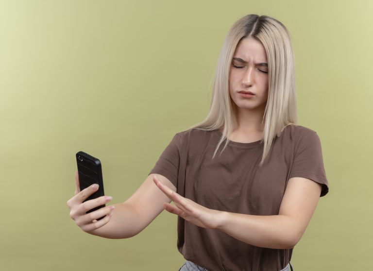 Holka drží telefon se zavřenýma očima