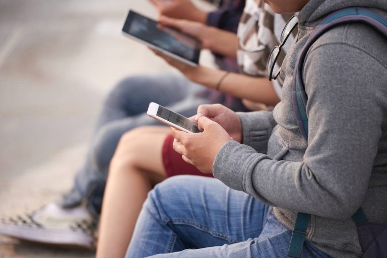 Závislost na sociálních sítích — mladí lidé scrollují na telefonech